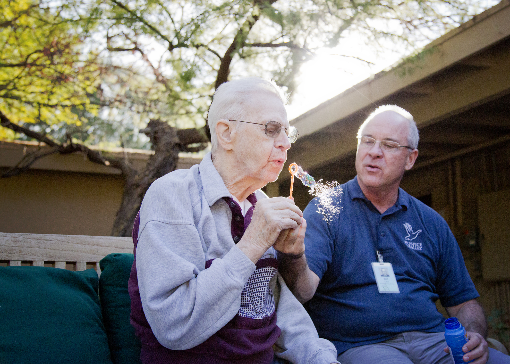 Male dementia patient blowing bubbles with volunteer at Gardiner Home