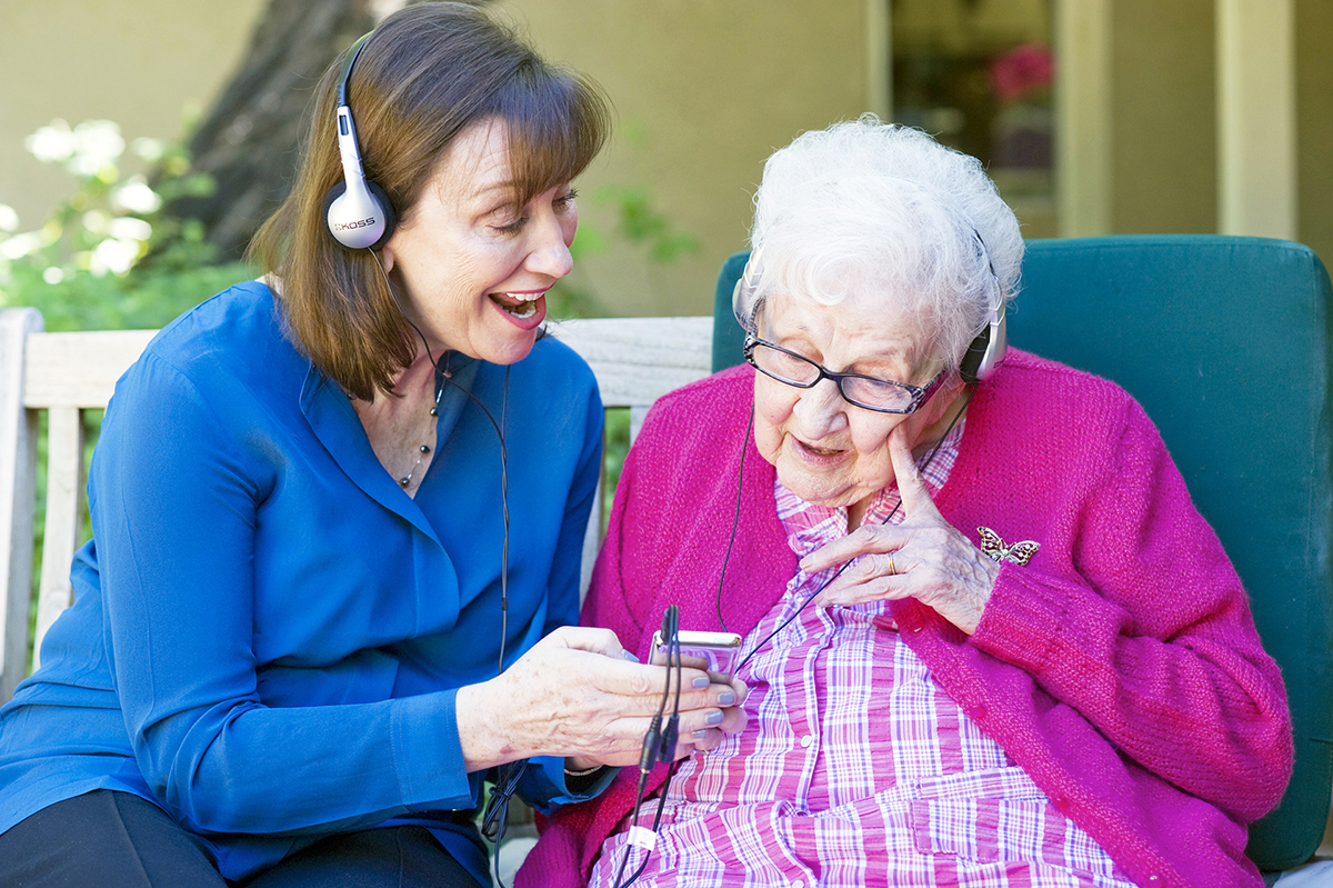 Maribeth Gallagher listens to music and sings with a dementia patient